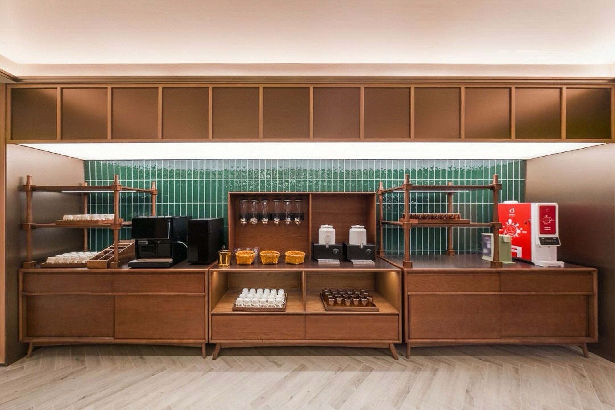 A kitchenette with a coffee machine, tea dispensers, and a refrigerator.