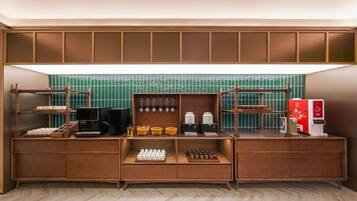 A kitchenette with a coffee machine, tea dispensers, and a refrigerator.