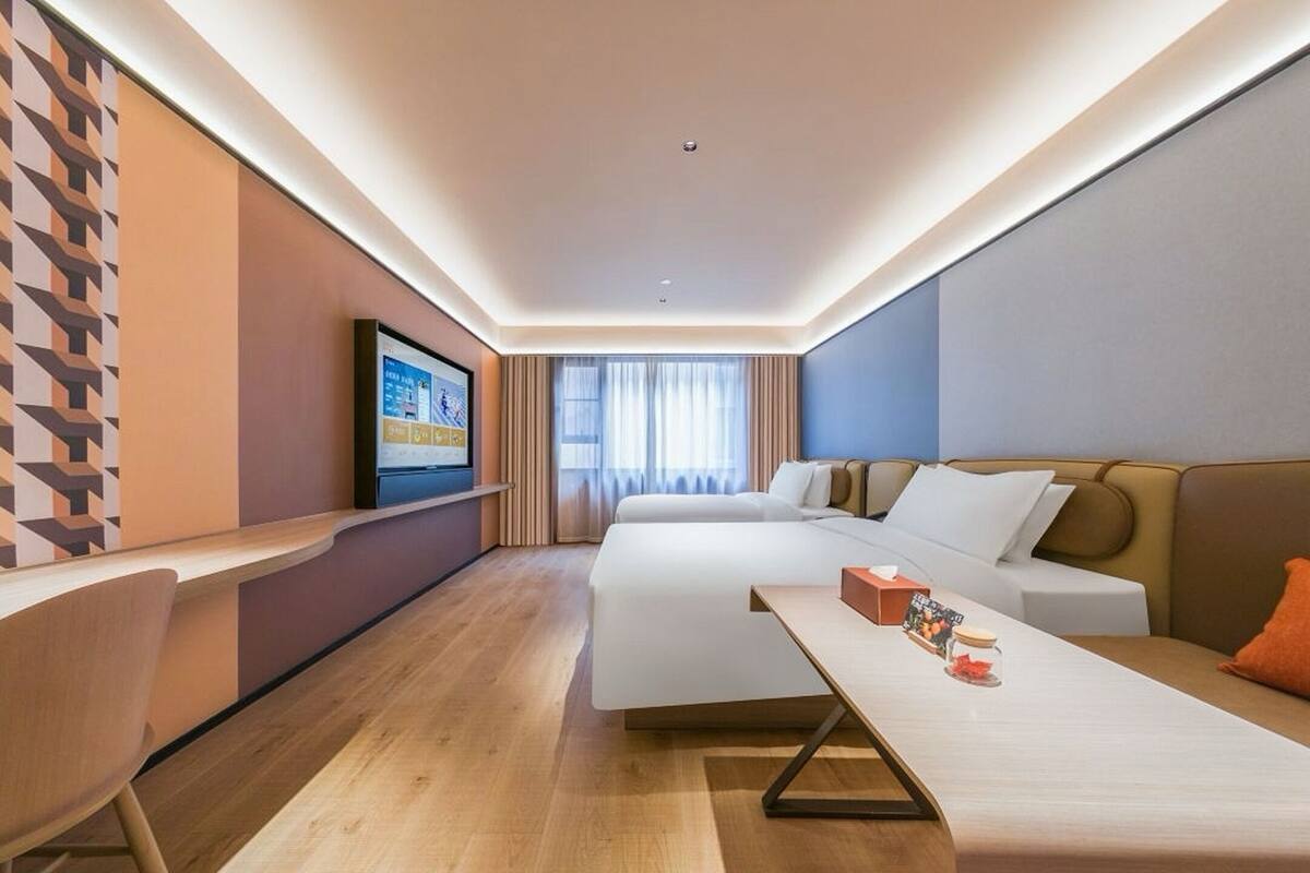 Una habitación de hotel moderna con una cama, un escritorio, un televisor y un sofá.