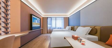 A modern hotel room with a bed, a desk, a TV, and a sofa.