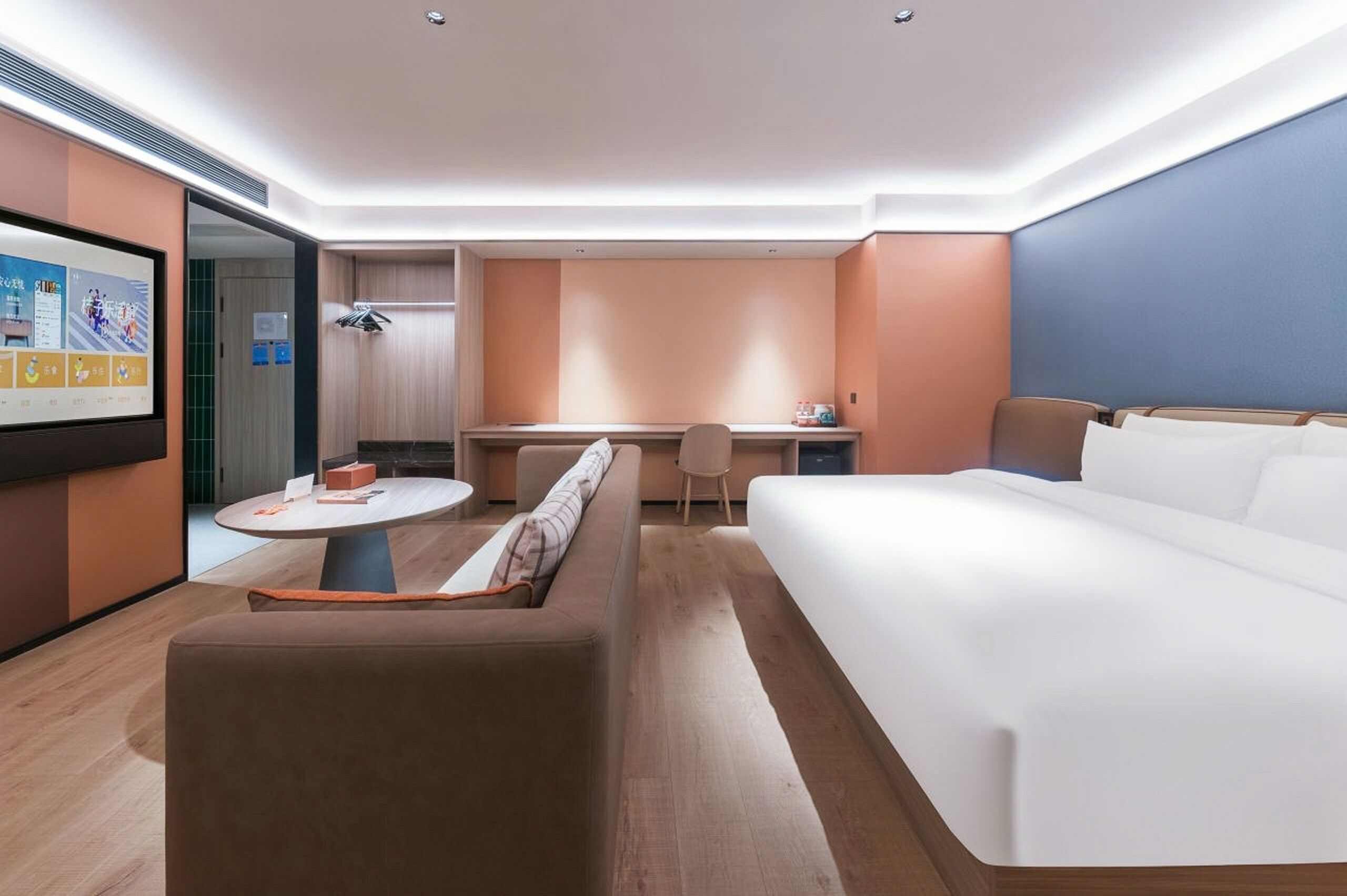 Una habitación de hotel moderna con una cama grande, un sofá, un escritorio y una pantalla de televisión que muestra un canal deportivo.