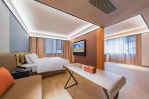 Una habitación de hotel moderna con una cama, un sofá, una mesita y un televisor en la pared.