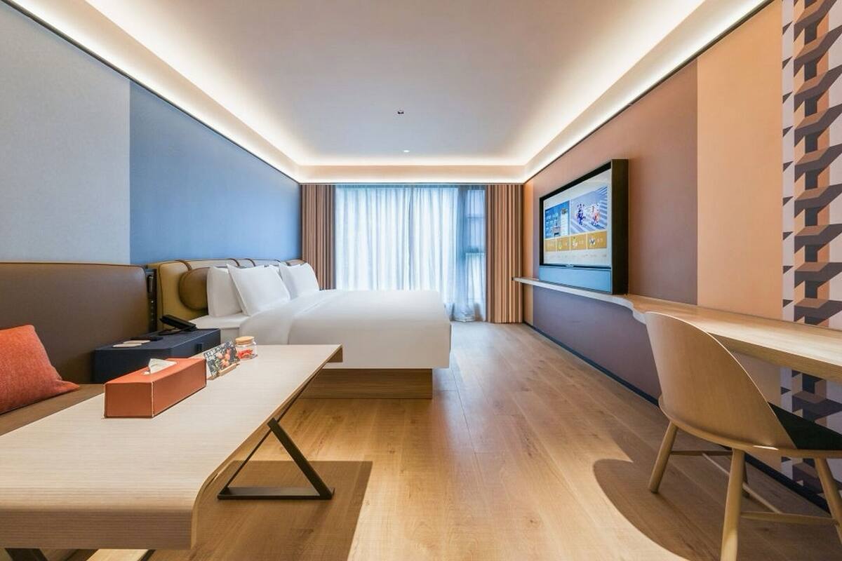 Una habitación de hotel moderna con una cama, un escritorio, una silla y un televisor.