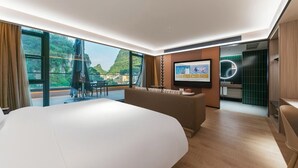 Una habitación de hotel moderna con una cama grande, televisión y balcón con vista a las montañas.