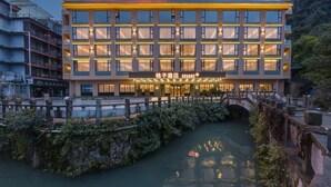 Un hotel con fachada moderna, varios pisos y un puente sobre una masa de agua.