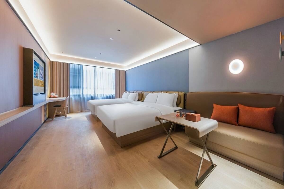 Una habitación de hotel moderna con una cama grande, un sofá, una mesita y un escritorio con una silla.
