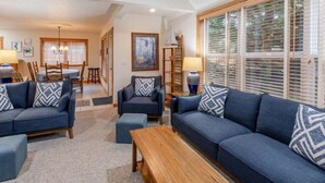 A living room with a sofa set, a coffee table, and a dining area with a table and chairs. - Seahorse -Steps to beach, 3 bed, bikes, fireplace. (Pacific City)