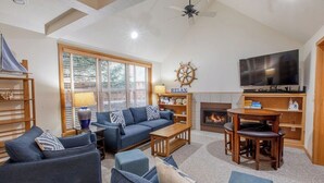A living room with a sofa, coffee table, and TV. There is a fireplace and a bookshelf. - Seahorse -Steps to beach, 3 bed, bikes, fireplace. (Pacific City)