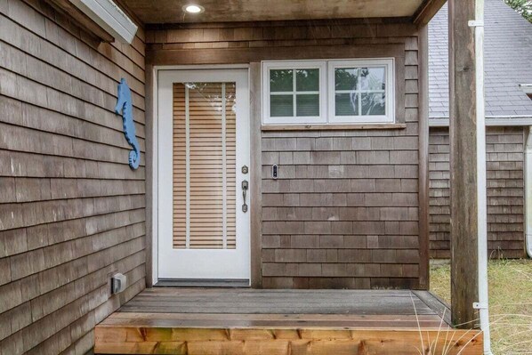 A wooden exterior with a white door and a small window above it.