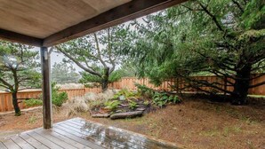 A wooden deck with a view of a landscaped garden area, including a wooden fence and various plants. - Seahorse -Steps to beach, 3 bed, bikes, fireplace. (Pacific City)