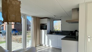 Une cuisine moderne avec des armoires blanches, un plan de travail noir et un porte-ustensiles suspendu.
