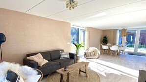 Un salon moderne avec un canapé, une table basse ronde en bois et un fauteuil en osier.