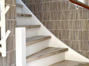 Eine Treppe mit Holzdielen und einer weißen Wand mit vertikalen Linien.
