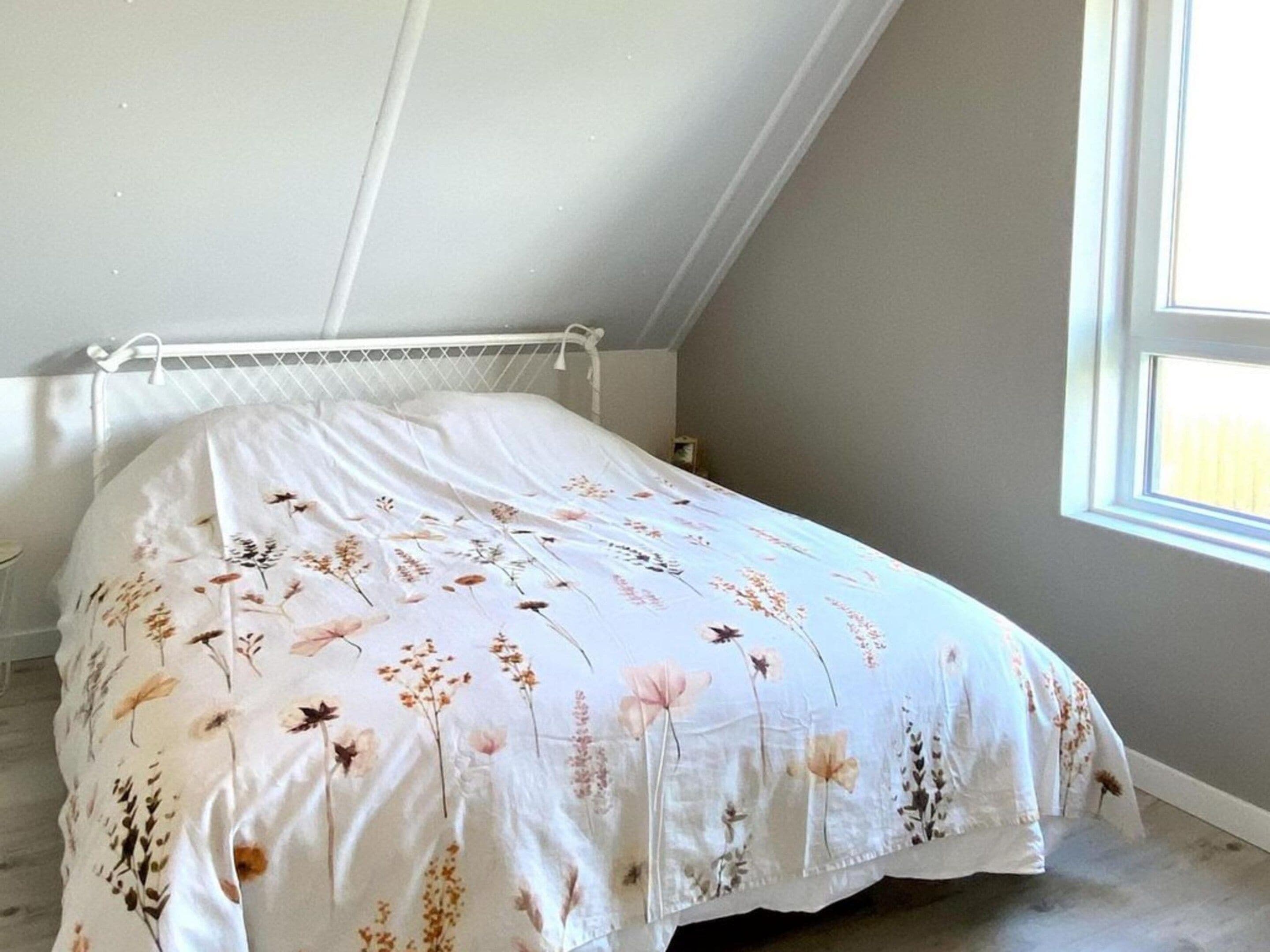 A bedroom with a bed, a window, and a radiator.