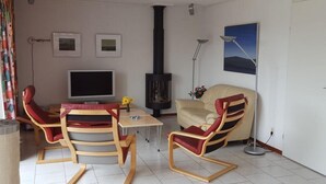A living room with a TV, a fireplace, and two rocking chairs. - Bungalow for 6 People, Near the Beach (Sint Maartensvlotbrug)
