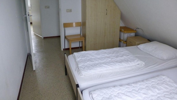 A small, simple room with a bed, a chair, and a wooden bench. - Bungalow for 6 People, Near the Beach (Sint Maartensvlotbrug)