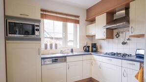 A modern kitchen with white cabinets, a built-in microwave, a gas stove, and a dishwasher. - Attractive Villa Close to Forest, Beach, sea (Sint Maartensvlotbrug)
