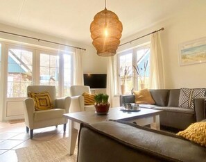 Un salon moderne comprenant un canapé, des fauteuils, une table basse et un téléviseur.