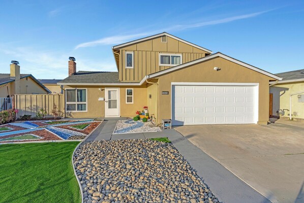 A two-story house with a garage, a well-maintained lawn, and a pebble garden.