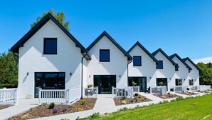 Una hilera de casas modernas, de color blanco con techos oscuros y barandillas blancas.