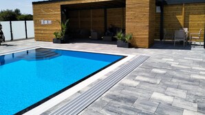 Un edificio moderno con zona de estar al aire libre cubierta y piscina.