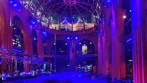 A spacious venue with a high ceiling and arched windows, featuring a central stage and multiple seating areas. - MARCO'S INTERLUDE Hotel Phu Quoc (Phu Quoc)