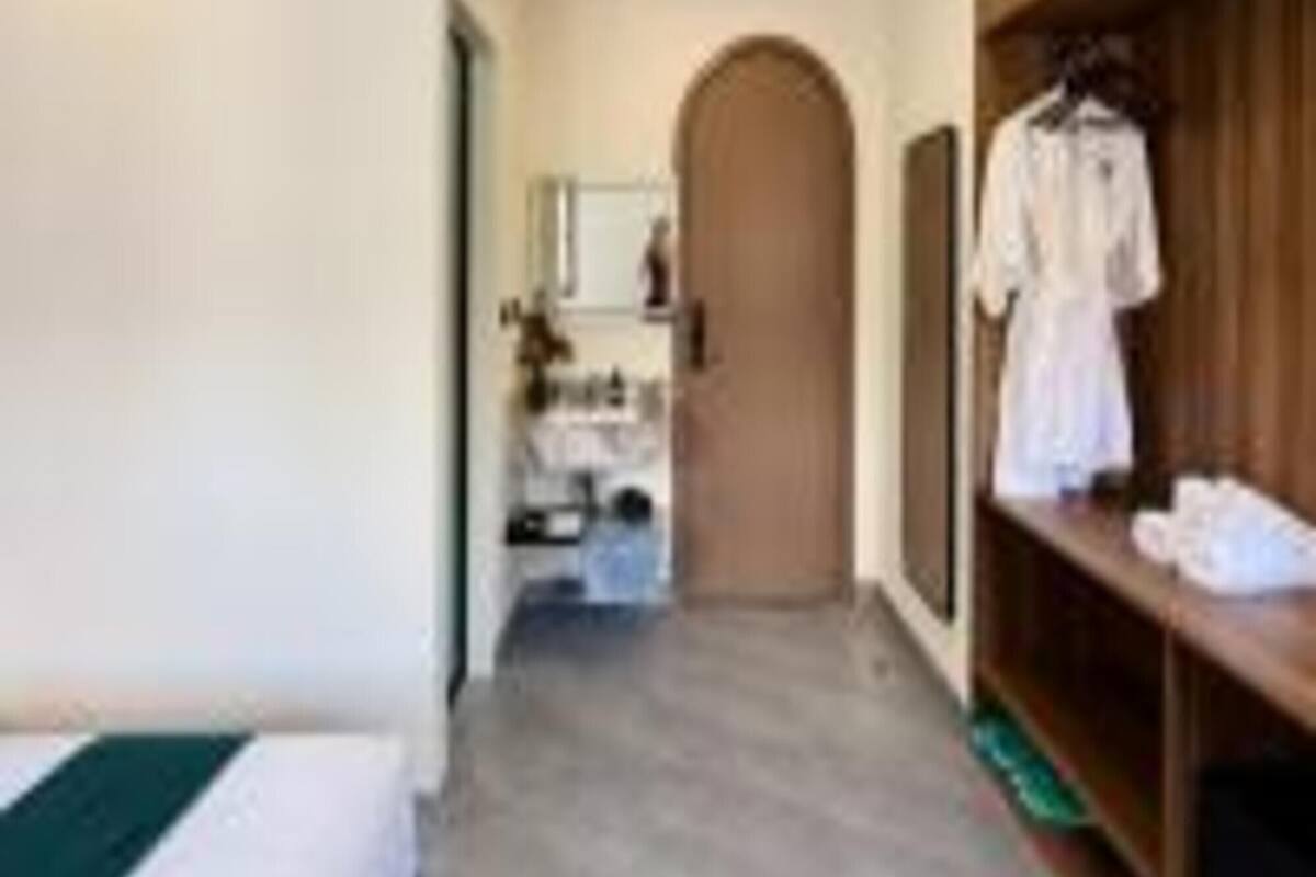 A hotel room with a bed, a wooden wardrobe, and a mirror.