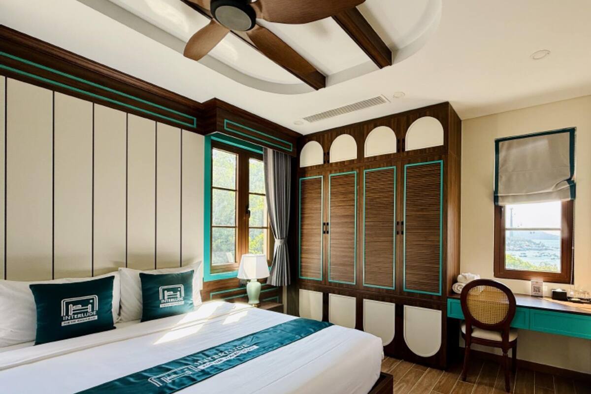 A hotel room with a large bed, a desk, and a view of the sea.
