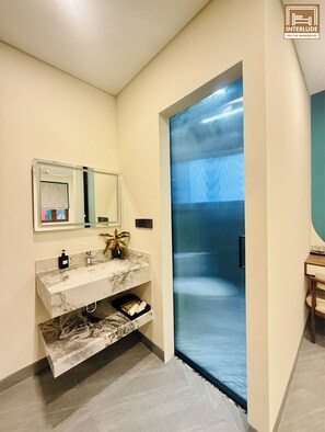 A modern bathroom with a marble vanity, a large mirror, and a frosted glass door. - MARCO'S INTERLUDE Hotel Phu Quoc (Phu Quoc)