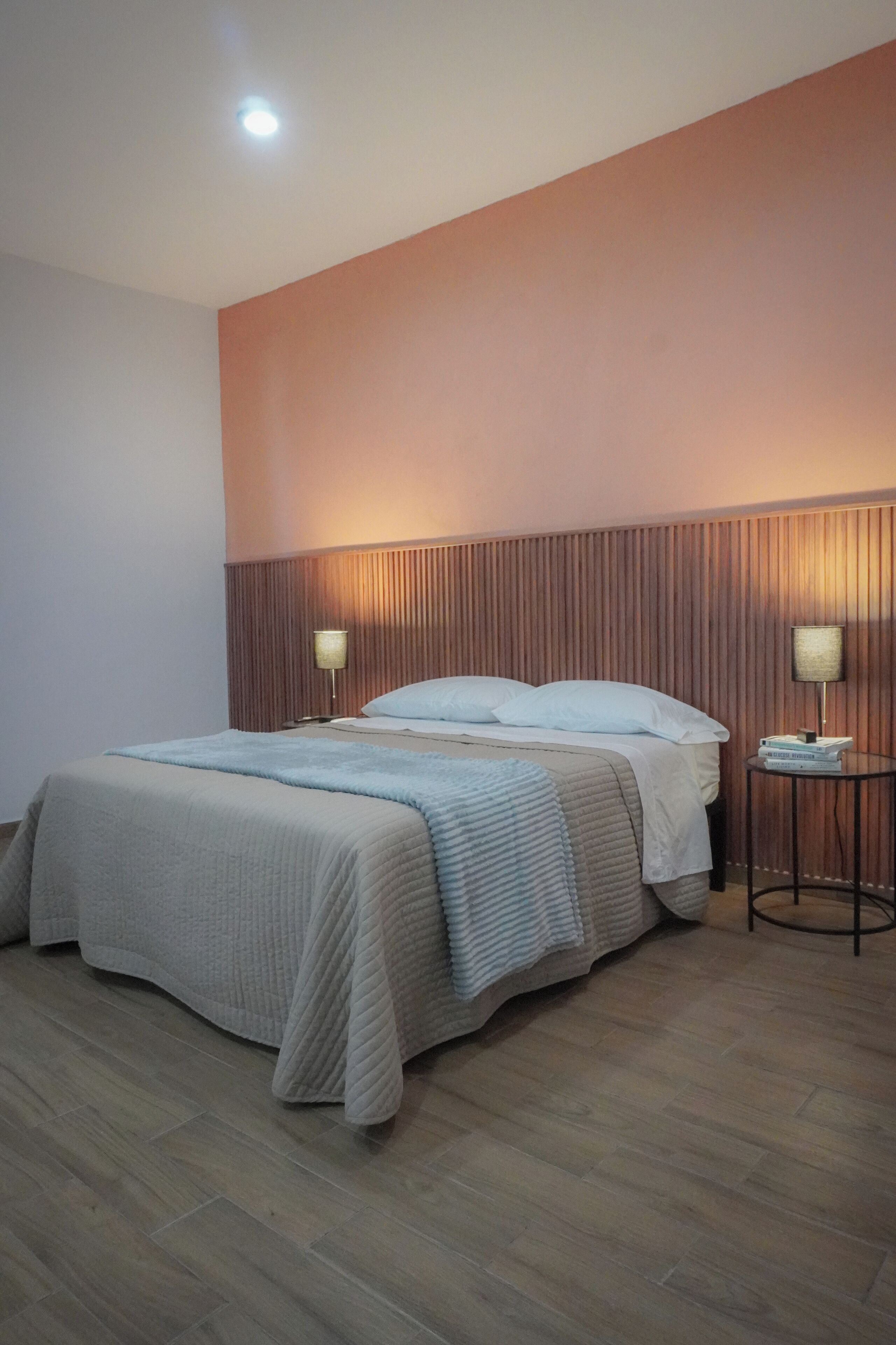 A neatly arranged bedroom with a bed, two bedside tables, and a wall-mounted light fixture.