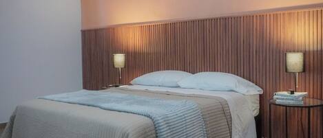 A neatly arranged bedroom with a bed, two bedside tables, and a wall-mounted light fixture.