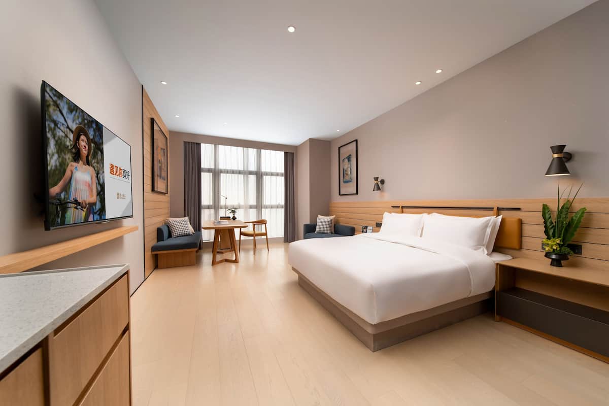 Een moderne hotelkamer met een groot bed, een bureau en een televisie.