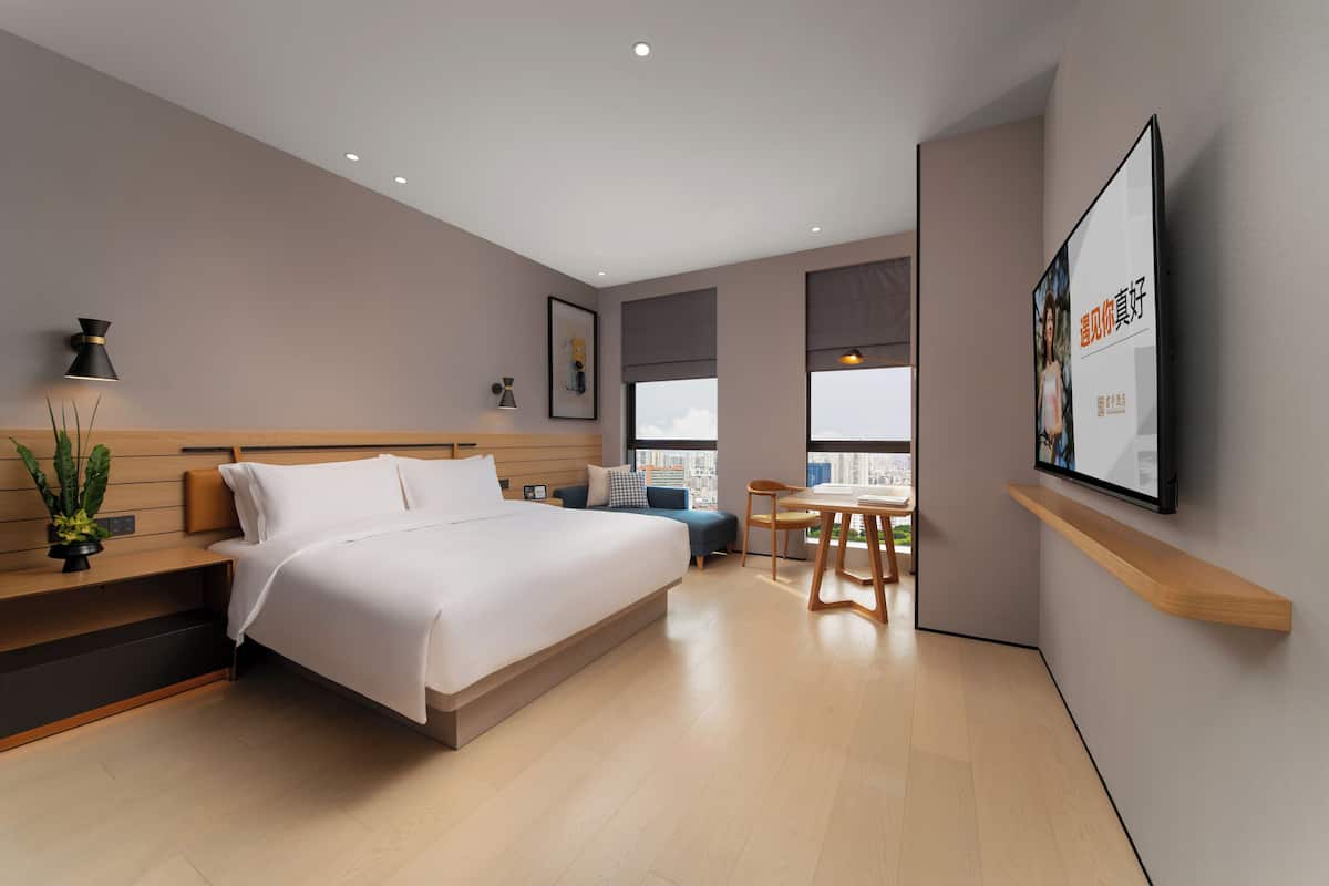 Een moderne hotelkamer met een groot bed, een bureau en uitzicht op de stad.