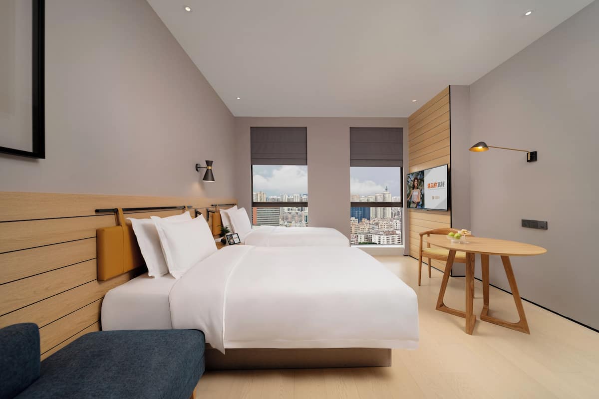 Een moderne hotelkamer met een groot bed, een tafeltje en uitzicht op de stad.