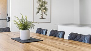 A wooden dining table with a potted plant, black placemats, and black cushioned chairs. - Large stylish home in Bendigo, perfect for families, close to sporting precinct  (Jackass Flat)