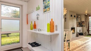 Ein Zimmer mit einem großen Fenster, einer weißen Tür und einer weißen Wand mit Regalen, die verschiedene Gegenstände tragen.