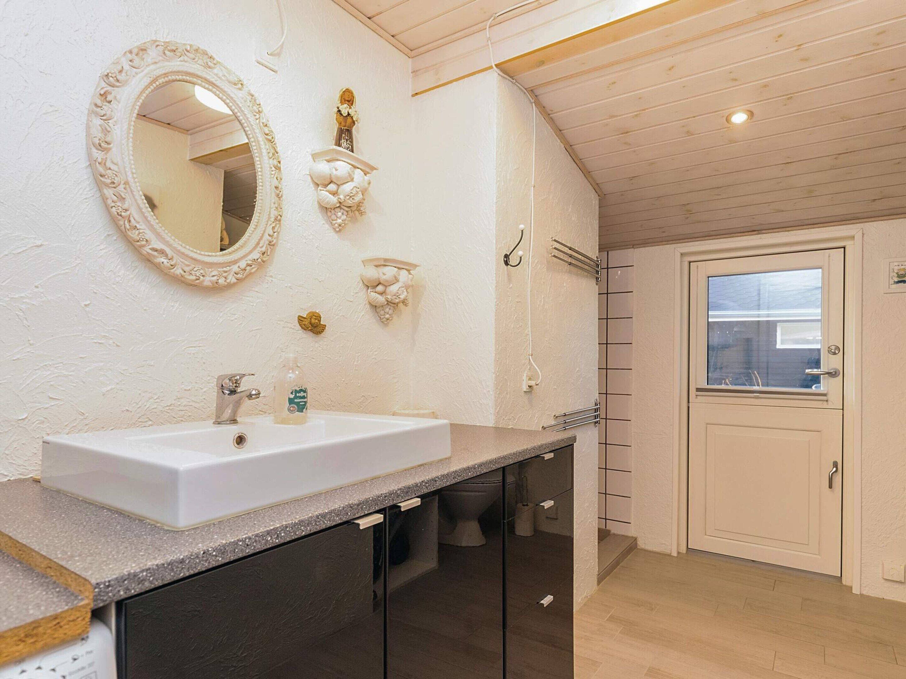 A bathroom with a white sink, a mirror, and decorative wall sconces.