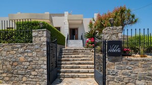 A stone-walled entrance with a gate leading to a staircase and a villa named "Villa Atheria".