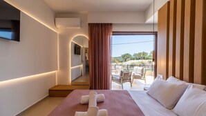 A hotel room with a bed, a balcony with outdoor seating, and a view of the landscape.