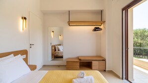 A hotel room with a bed, a wooden nightstand, a mirror, and a balcony with a railing.