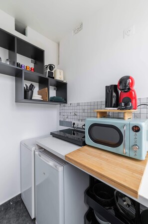 A compact kitchen with a microwave, coffee maker, and a small refrigerator.