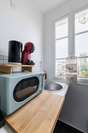 A kitchen with a microwave, a kettle, and a sink. - Studio Cosy proche tour Eiffel - Paris 7 - 2P (Paris)