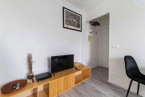 Un soggiorno moderno con una televisione a schermo piatto su un mobile in legno, un quadro appeso al muro e una poltrona nera.