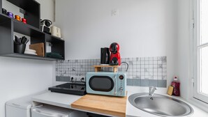 Una cocina compacta con microondas, tostadora y fregadero.