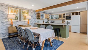 Eine moderne Küche mit Essbereich, mit Holzboden, Marmorfliesenspiegel und einem blau gemusterten Teppich.
