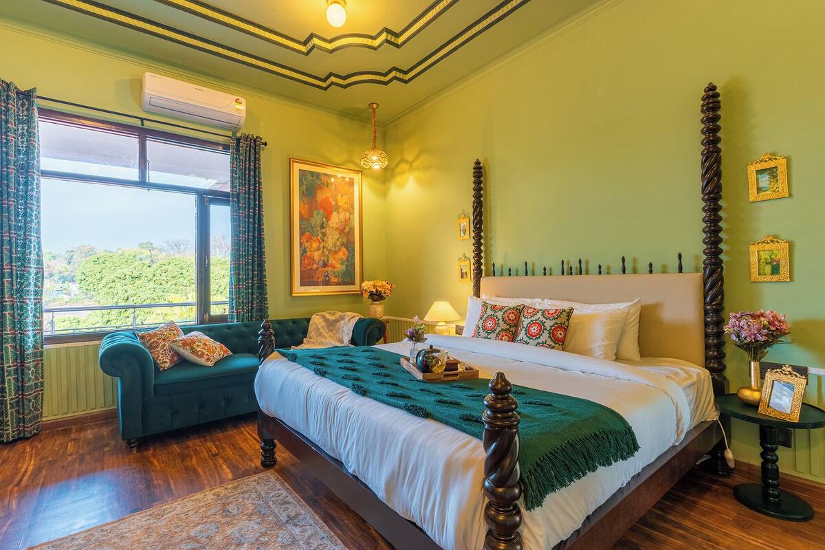 A well-appointed bedroom with a large bed, a green sofa, and a view of the outdoors.