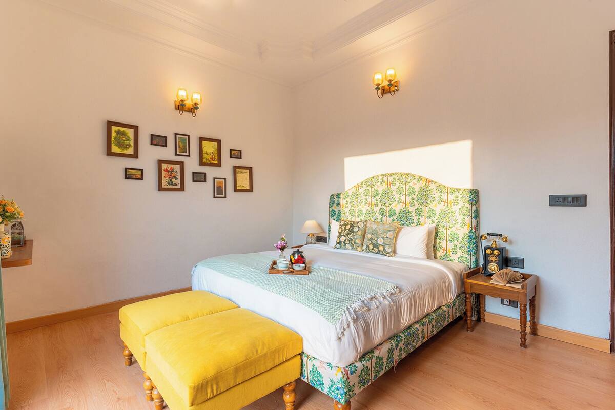 A bedroom with a bed, a nightstand, a lamp, a telephone, and wall-mounted lights.