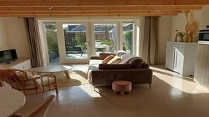 Een gezellige woonkamer met een bank, een klein rond tafeltje en een televisie.