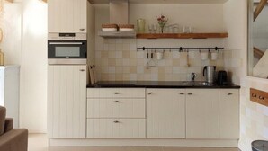 Een moderne keuken met witte kastjes, een inbouwoven en een houten plafond.
