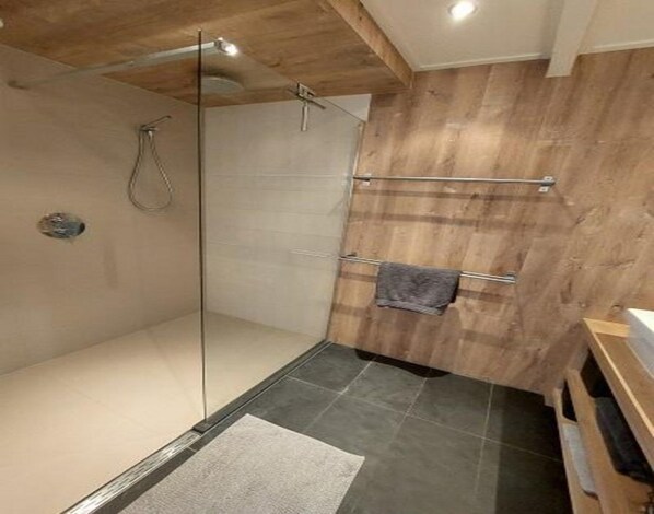 A modern bathroom with a glass shower enclosure, wooden wall paneling, and a towel rack. - Dirkshorn Holiday Home for 4 (Dirkshorn)